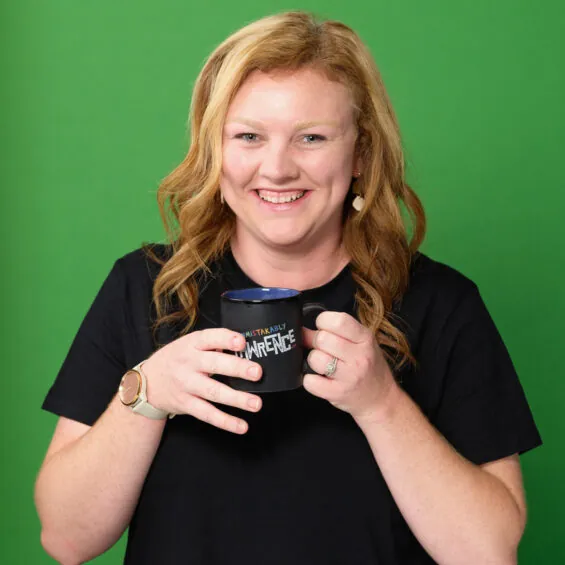 Young white female, smiles at camera with coffee cup in hand