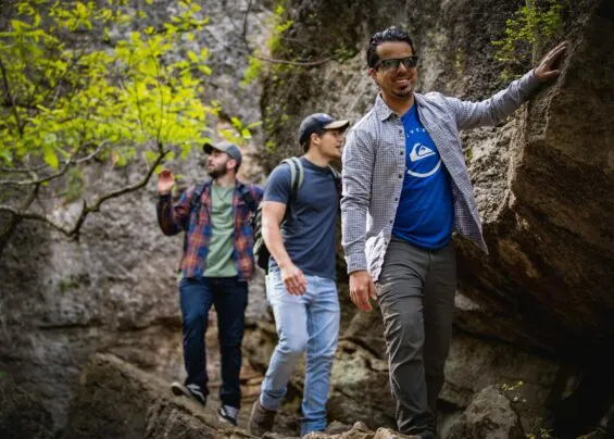 Three friends hike in Elk City State Park along stunning rock structures.