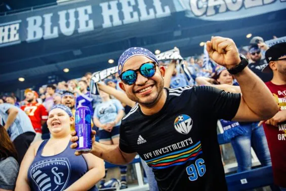 Man in bandana and sunglasses cheers on the KC soccer team from the stands.