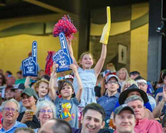 Young Wichita Wind Surge fans holding foam fingers in the air to cheer on their team.